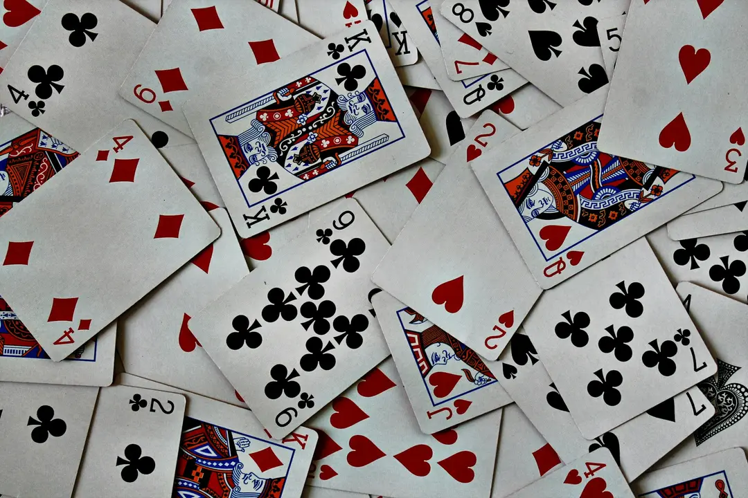 Playing cards of every suit scattered face up across a table